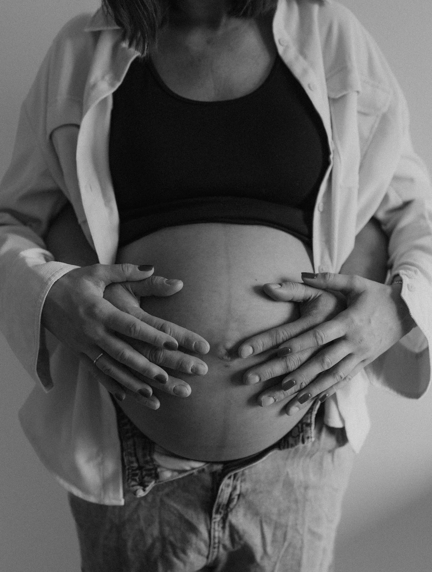 Hände eines Paares auf dem schwangeren Bauch